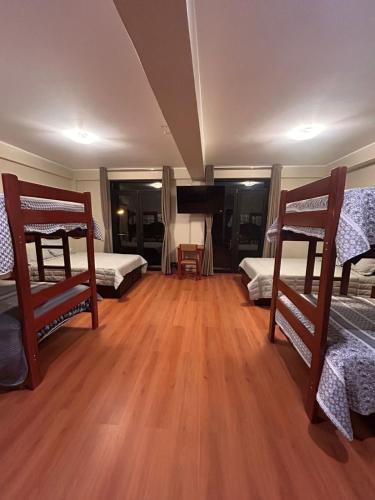 a room with three bunk beds and a wooden floor at Hotel Makita in Muquiyauyo