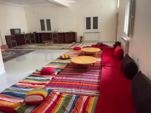 a living room with a red couch with pillows and tables at Adam House in Ghardaïa