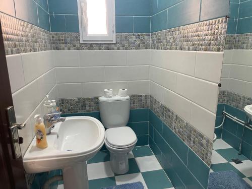 a blue and white bathroom with a toilet and a sink at Adam House in Ghardaïa