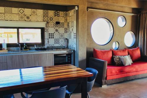 a dining room with a table and a red couch at Complejo Piuquenes Valle de Uco in Vista Flores