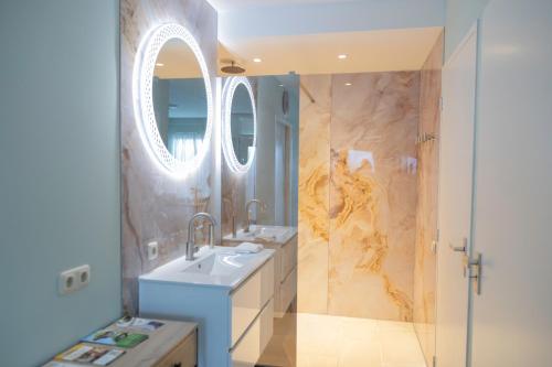 a bathroom with a sink and a shower with a mirror at Dromen op de Veluwe in Putten