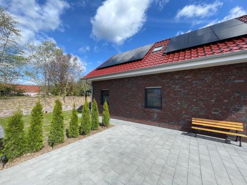 a bench next to a brick building with a solar roof at Seeidylle in Geeste