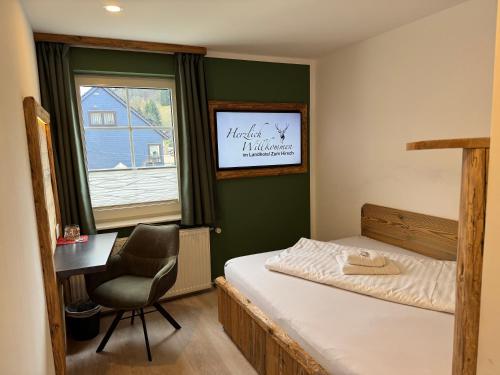 a bedroom with a bed and a desk and a window at Landhotel Zum Hirsch in Unterweißbach