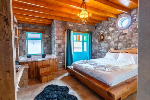 a bedroom with a bed and a stone wall at Tetka Konukevi in Ayvalık