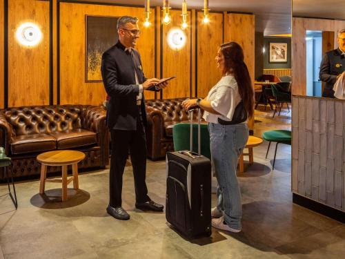 a man standing next to a woman with a suitcase at Novotel Birmingham Airport Terminal Building - NEC in Bickenhill