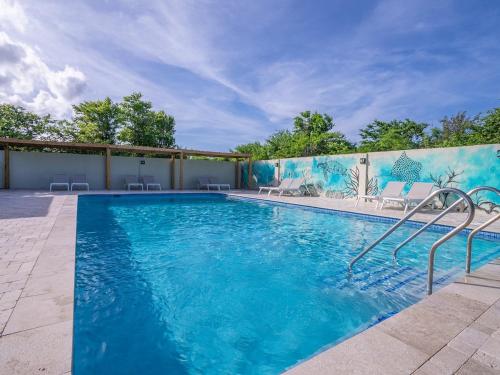 a swimming pool with blue water in a yard at Trupial - The green flamingo in Willibrordus