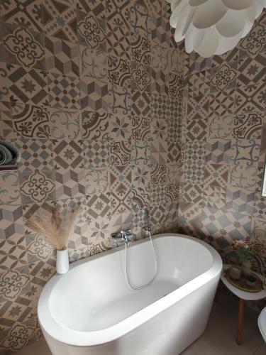 a white tub in a bathroom with tiles at Ta'Roza Modern Apartment with Balcony & Distant Sea Views - Xaghra Gozo in Xagħra