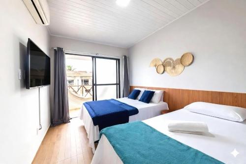 a hotel room with two beds and a television at Casa06Frances com decoração moderna à 8min de carro da praia do frances com piscina PRIVATIVA, 03 quartos com AR in Marechal Deodoro