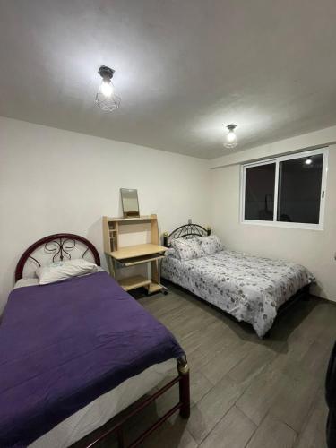 a bedroom with two beds and a desk and a window at Oaxaca Express, comodidad y cercania al centro in Santa Lucía