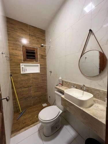 a bathroom with a toilet and a sink and a mirror at Casa Temporada Trairi in Trairi