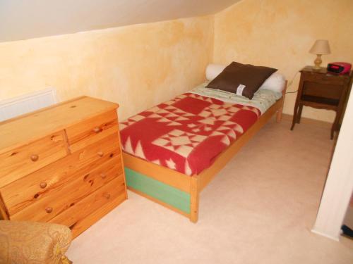 a small bedroom with a bed and a wooden dresser at Gîte La Lieutenance in Saint-Pourçain-sur-Sioule
