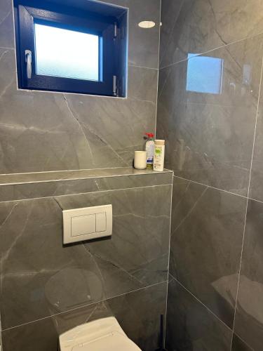 a bathroom with a toilet and a window at Villa Violand in Limanu