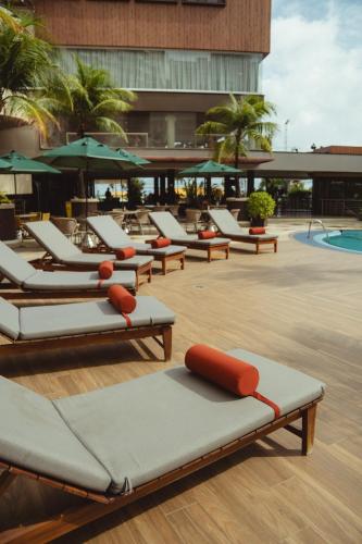 a row of lounge chairs and a swimming pool at Afago Mareiro Hotel in Fortaleza