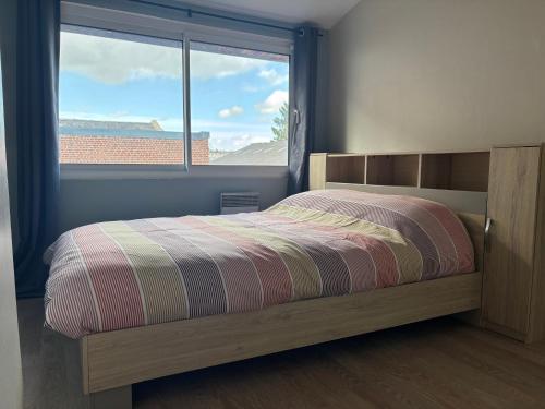 a bedroom with a bed and a large window at Le Saint Sauveur - centre ville in Péronne