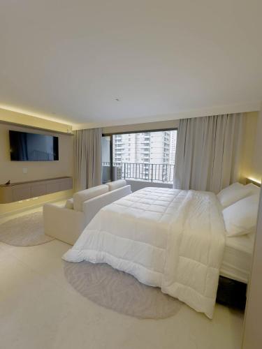 a white bedroom with a large bed and a couch at FR1307B Estúdio alto padrão com cama king e garagem in Goiânia