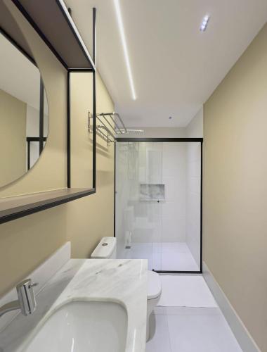 a bathroom with a sink and a toilet and a mirror at FR1307B Estúdio alto padrão com cama king e garagem in Goiânia