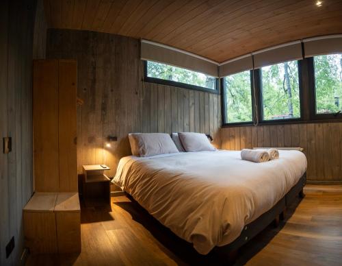 a bedroom with a large bed in a room with windows at Roble Viejo Lodge in Las Trancas