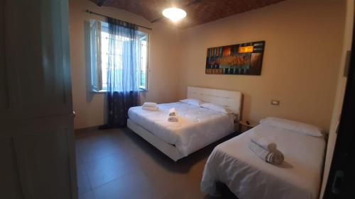 a bedroom with two beds and a window at Cascina San Giulio in San Damiano dʼAsti