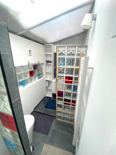 a bathroom with a toilet and a room with shelves at MataDoora in Nîmes