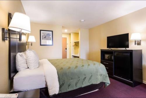 a hotel room with a bed and a flat screen tv at Urban Inn & Suites in Boise