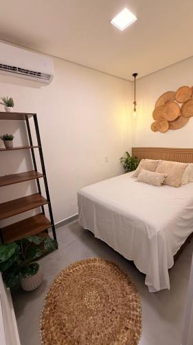 a bedroom with a white bed and a rug at Flat aconchegante em Juquehy! Com piscina! in Praia de Juquehy