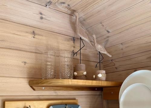 a shelf with glasses on a wooden wall at Gut Osterhausen in Butjadingen