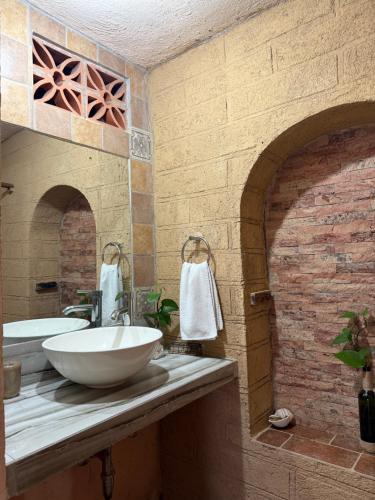 a bathroom with a white sink and a brick wall at Hotel SPA Campestre Los Adobes in Taxco de Alarcón