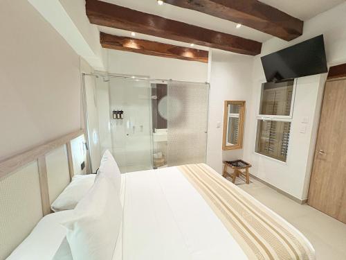 a white bedroom with a large bed and a shower at Casa Helena Getsemaní in Cartagena de Indias