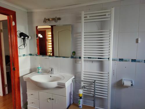 a white bathroom with a sink and a mirror at Casa amoblada en Punta arenas in Punta Arenas