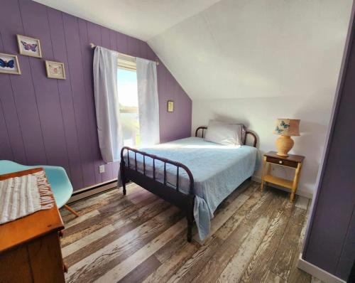 a bedroom with purple walls and a bed and a window at Oneida Lakeside Retreat in Bridgeport