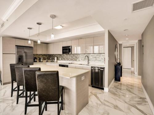 a kitchen with a large island with bar chairs at Luxury 3BR Water view 18th-Floor Deck Pool in Hallandale Beach