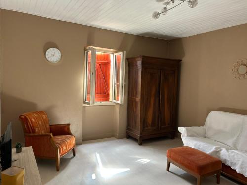 a living room with a bed and a chair and a clock at GÎte à la ferme in Lalinde