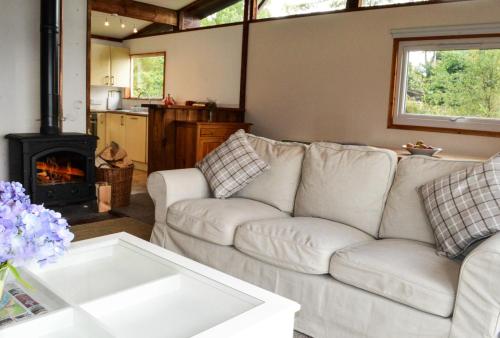 a living room with a white couch and a fireplace at Cockleshell Lodge in Otter Ferry