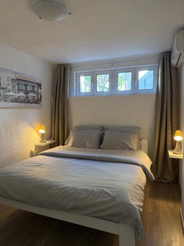 a bedroom with a large bed with two windows at Perla Sea View in Budva