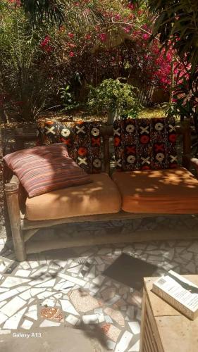 a bench with cushions sitting on a patio with flowers at Arijaana Guest Studio in Gunjur