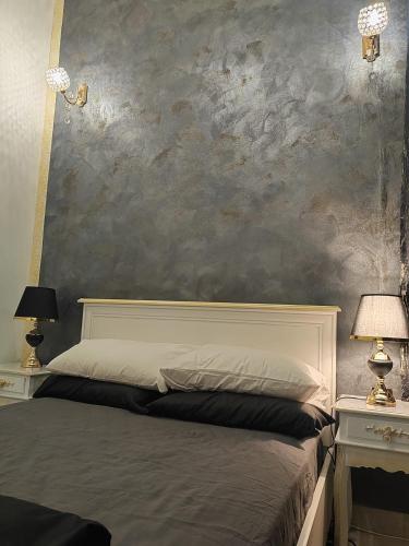a bedroom with a bed and two lamps and a wall at Baroque Palace Black Diamond in Arad
