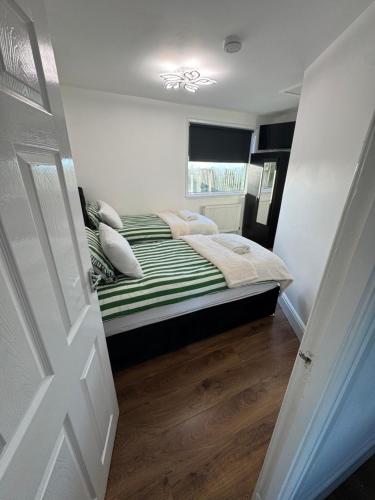 a bedroom with a bed with a green and white comforter at Roman apartment in Skegness