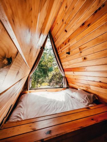a small bed in a wooden room with a window at WANDER CABIN La Marquesa in La Marquesa