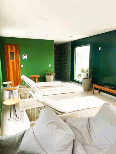 a living room with white furniture and green walls at Loft Moderno Vista Mar - 14 Minutos De Copacabana in Rio de Janeiro