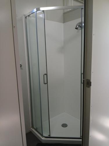 a shower with a glass door in a bathroom at Harbour Heights Cabins in Athenree