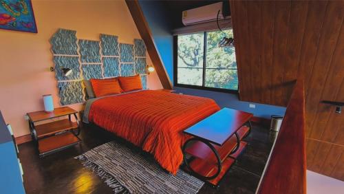 a bedroom with a bed with an orange bedspread and a window at Coffee Cabins - Cabin 4 in Boquete