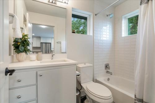 a white bathroom with a toilet and a sink and a tub at Modern Downtown Apt Fast Wi-Fi & Parking in Austin