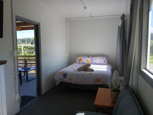 a small bedroom with a bed and a window at Harbour Heights Cabins in Athenree
