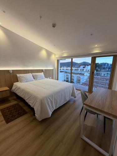 a bedroom with a white bed and a large window at Art Deco 882 in Cuenca