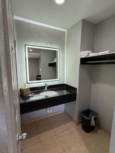 a bathroom with a sink and a large mirror at Relax Inn Bryan College Station in Bryan