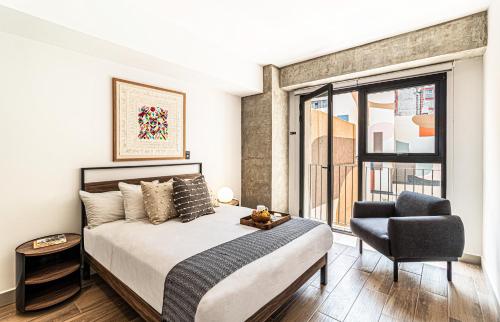 a bedroom with a bed and a chair and a window at Kukun Reforma & Downtown in Mexico City