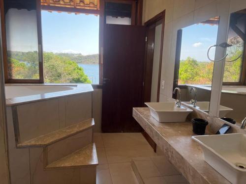 a bathroom with two sinks and a large window at rancho california rancho beira d'água Delfinopolis in Delfinópolis