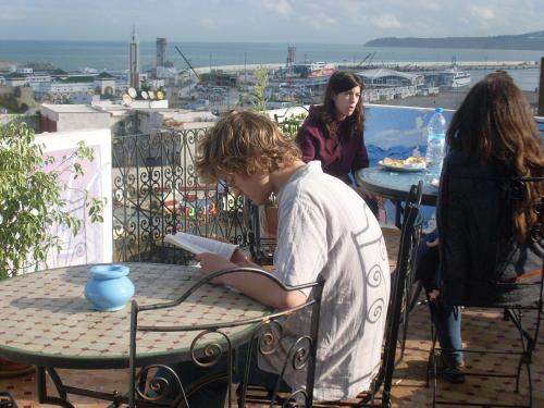 a man sitting at a table reading a book at The Medina Hostel in Tangier