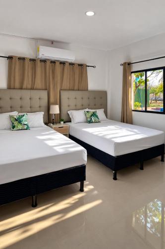 a bedroom with two beds and a window at Hotel Termaland in Atiquizaya