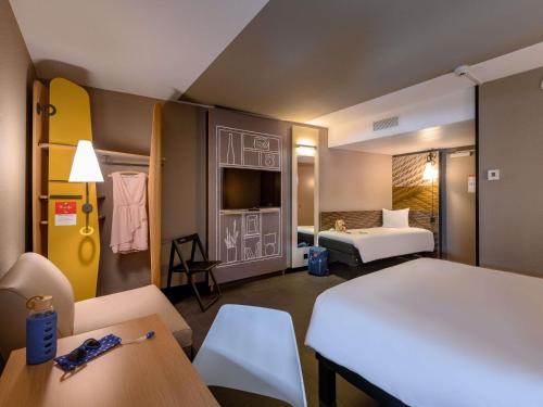 a hotel room with two beds and a table and chairs at ibis Zürich City West in Zurich